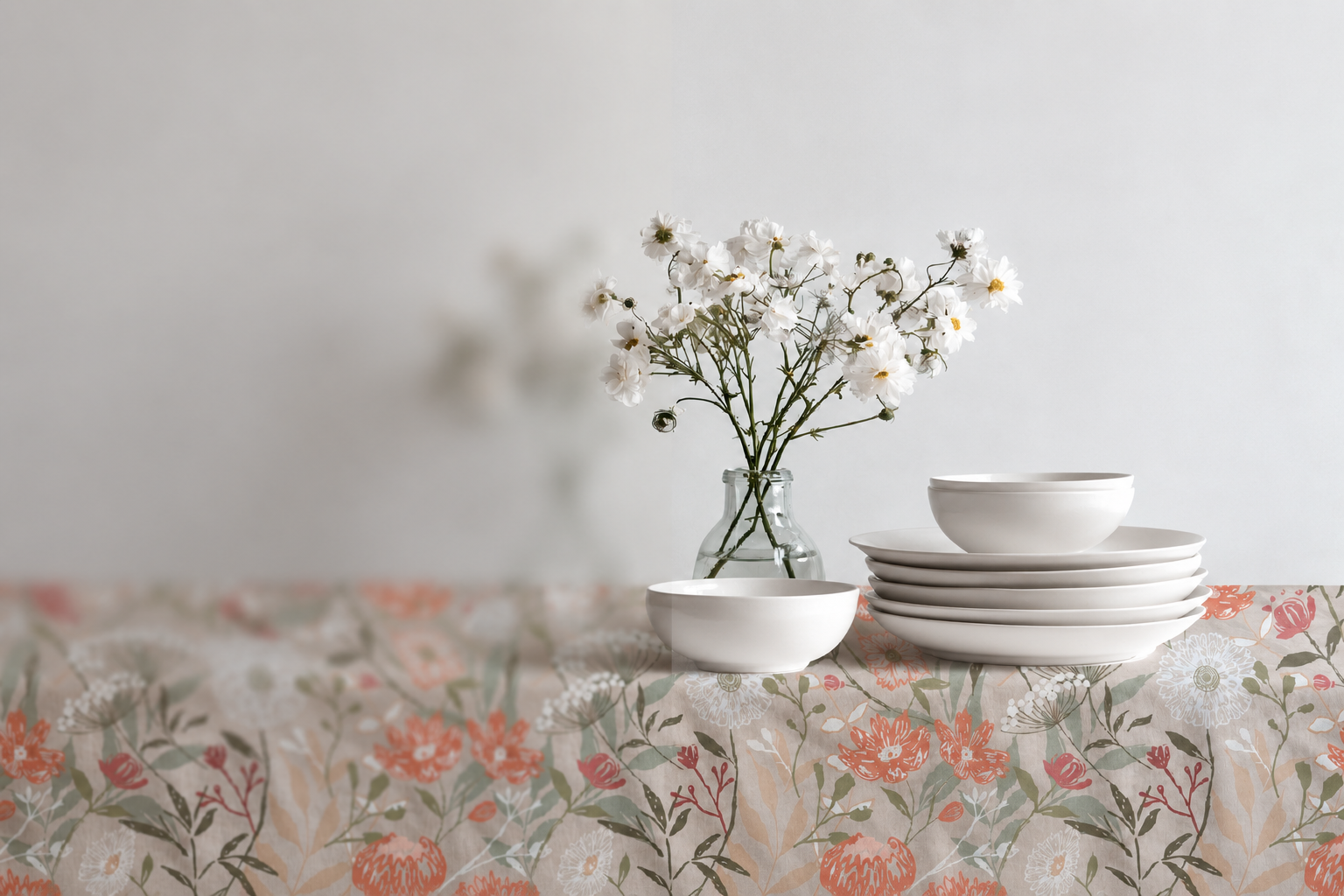 Floral pattern on a linen tablecloth with white dishes and a vase of delicate flowers in a neutral interior