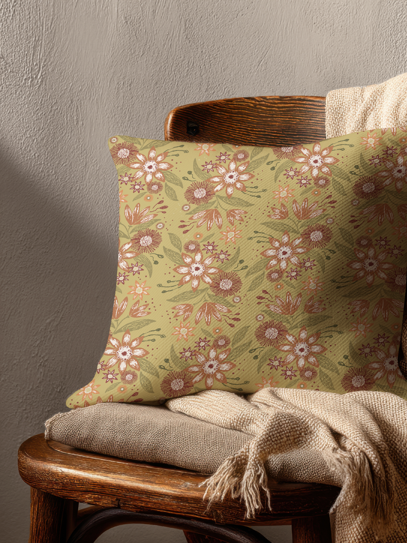 Wooden armchair with a decorative floral cushion featuring the Garden Reverie pattern in the Heritage Garden colorway, styled with a soft brown throw.