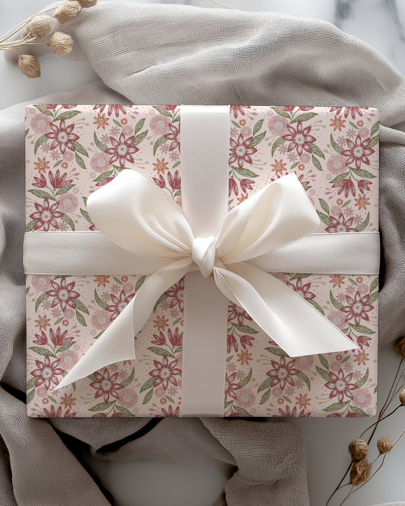 Gift box wrapped in the Garden Reverie floral pattern from the Botanical Reverie collection, featuring delicate dusty rose, terracotta and sage green flowers and foliage on a warm ivory background, finished with a white ribbon.
